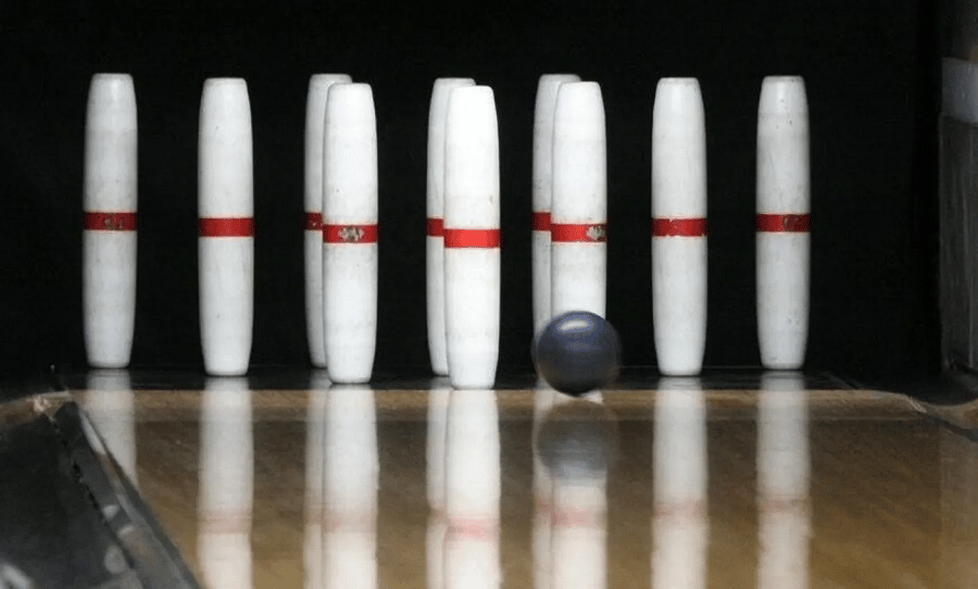 Candlepin bowling ball in front of standing pins